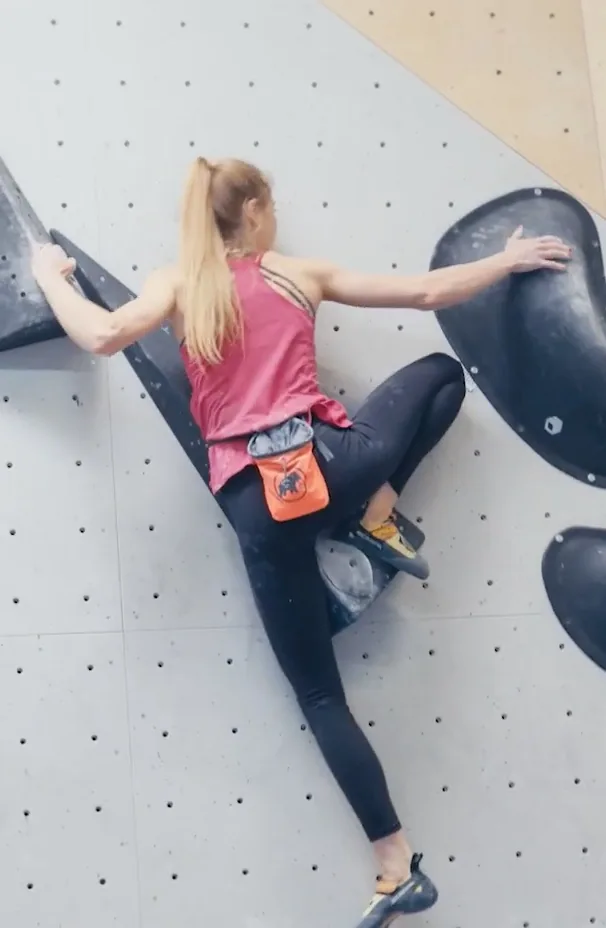Hannah Meul an der Kletterwand — Social Video für Allianz Hannah Meul klettert von hinten gesehen an einer steilen grauen Wand, den orangefarbenen Chalkbag am Gurt