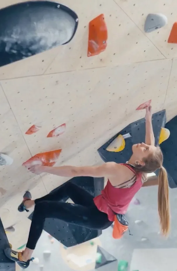 Athletenporträt für Allianz × Olympia: Hannah Meul am Überhang Aus dem Athletenporträt für Allianz × Olympia: Hannah Meul hängt unter dem Überhang und greift weit nach oben, das Bein auf einem schwarzen Volumen