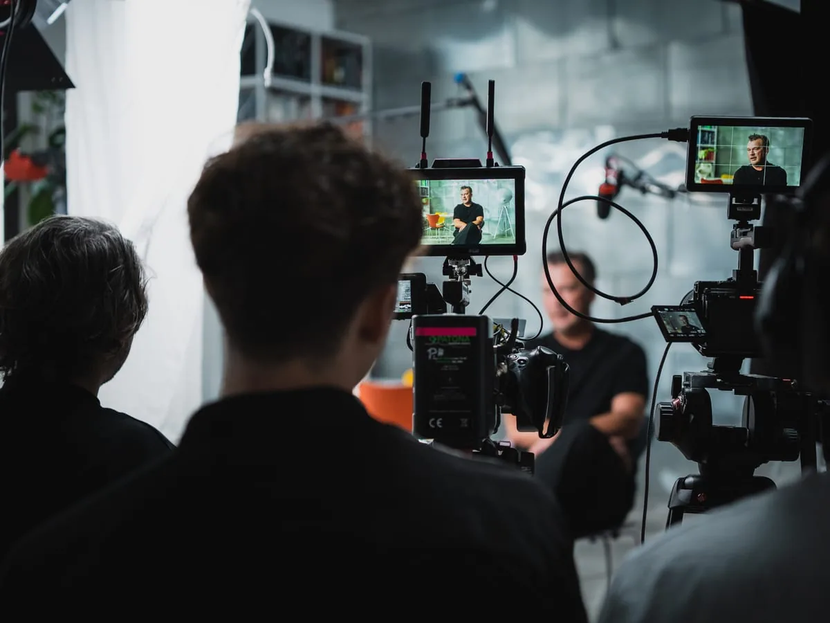 Content creation on set: looking over the team’s shoulders at two monitors, the same man in interview on both, camera and boom between them
