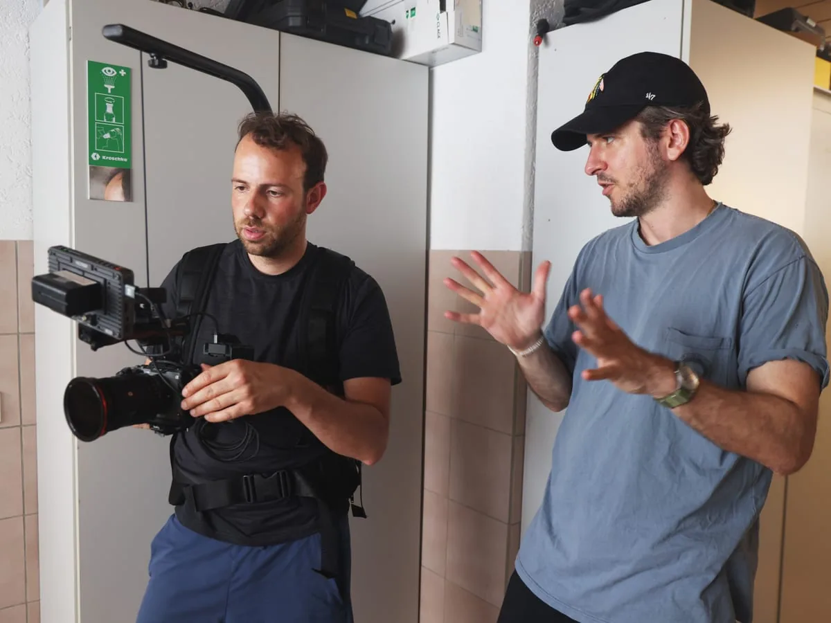 Two men at work: one carries the camera on a body rig, the other explains the next set-up