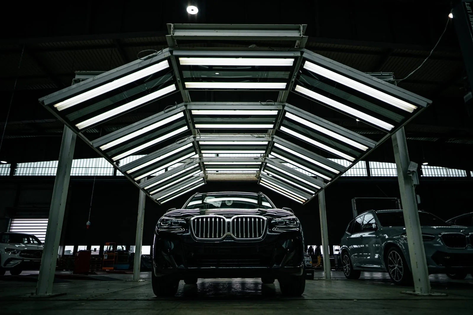 Werksfotografie für Formel D: SUV unter dem Lichtbogen Unternehmensfotografie für Formel D: ein SUV unter einem Bogen aus Leuchtstoffröhren, das Licht spiegelt sich im Lack