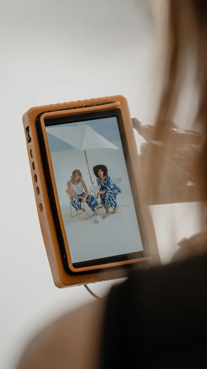 Over the shoulder: two models under a parasol on the orange field monitor