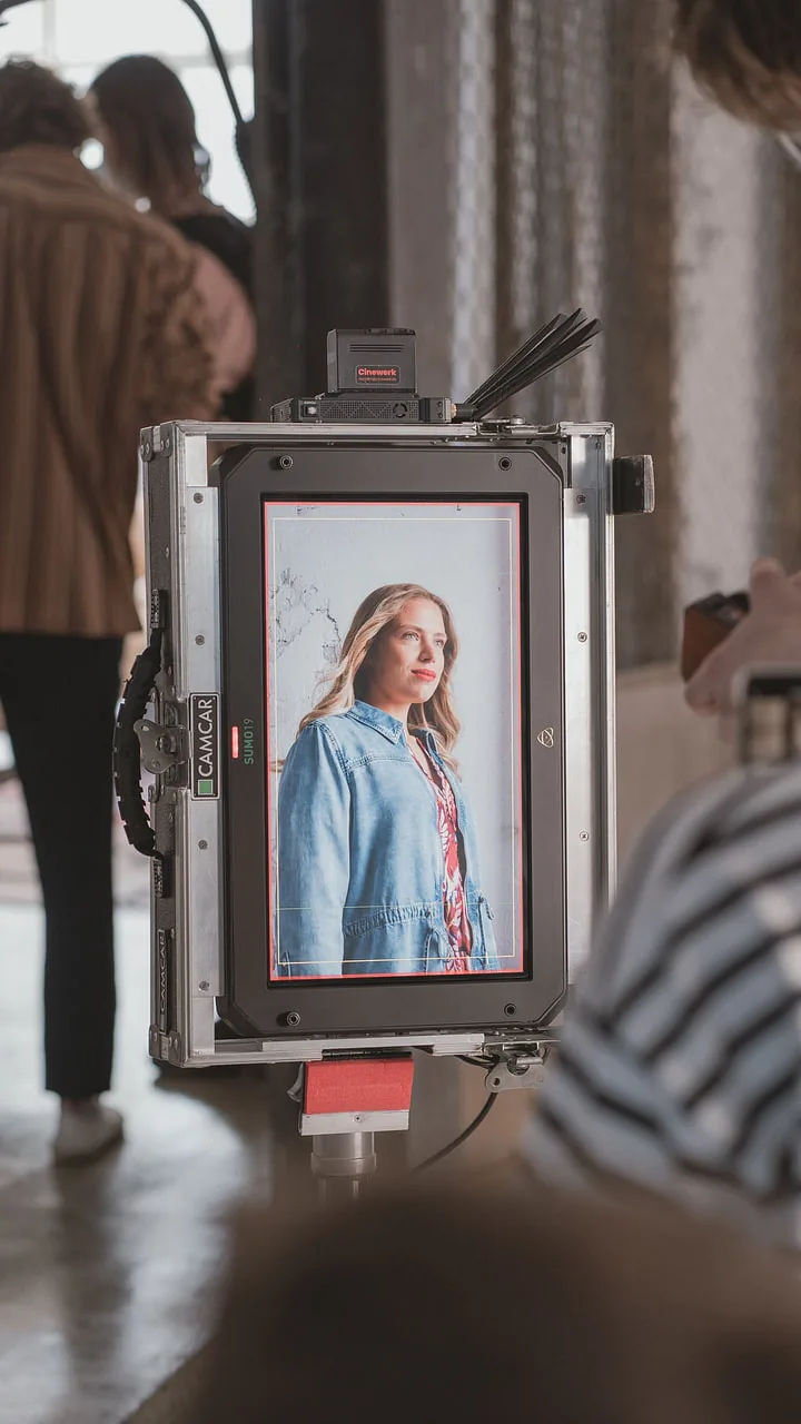 Monitor in a flight case showing a model in a denim jacket, the crew blurred in the hall behind