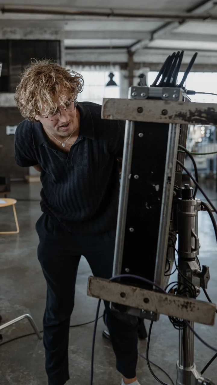 A crew member bending over the gear on the stand, the empty hall behind